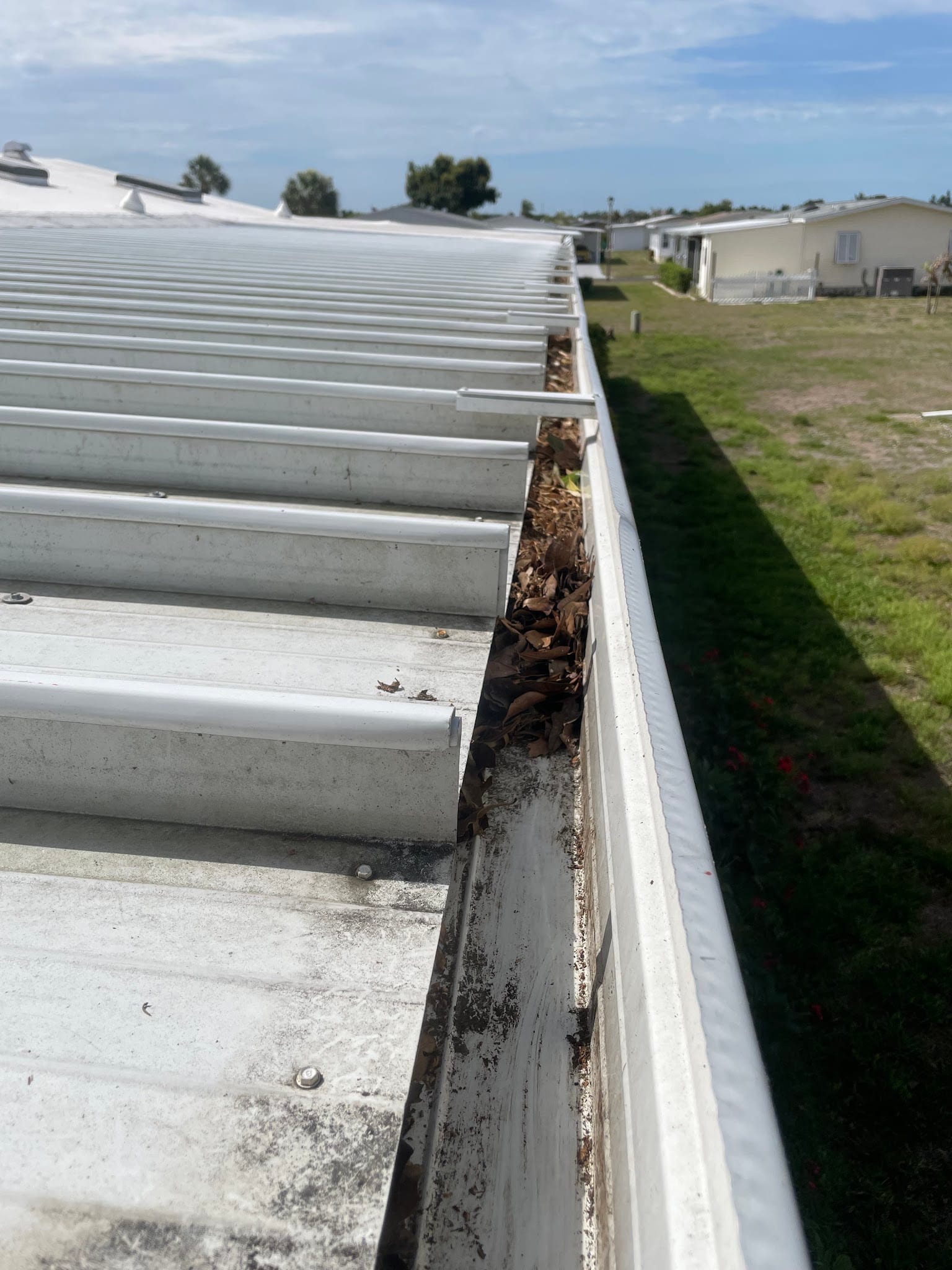 Metal roof gutter packed with dry leaves and debris in Port Charlotte