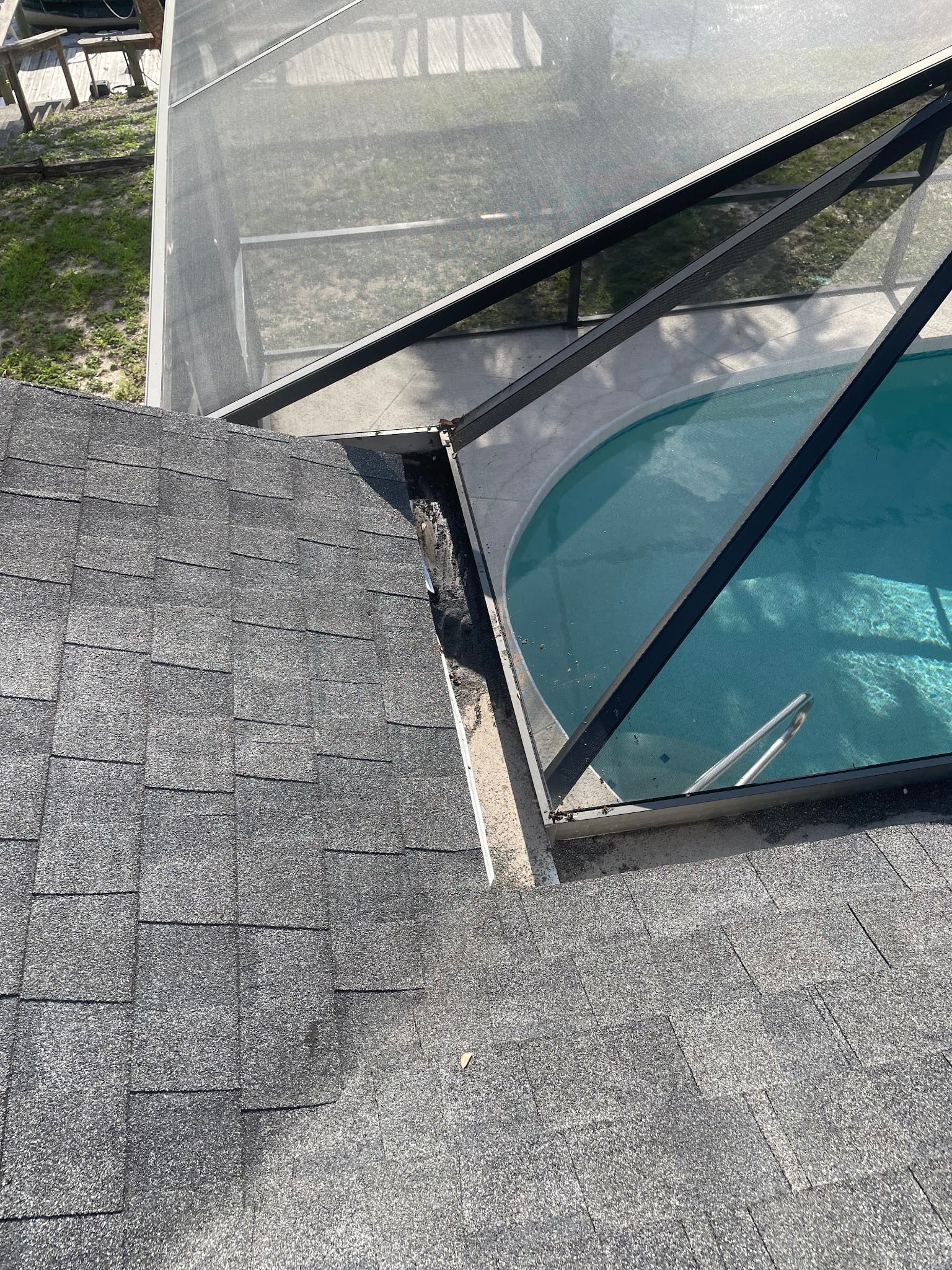Clogged gutter with debris buildup where roof meets pool screen enclosure