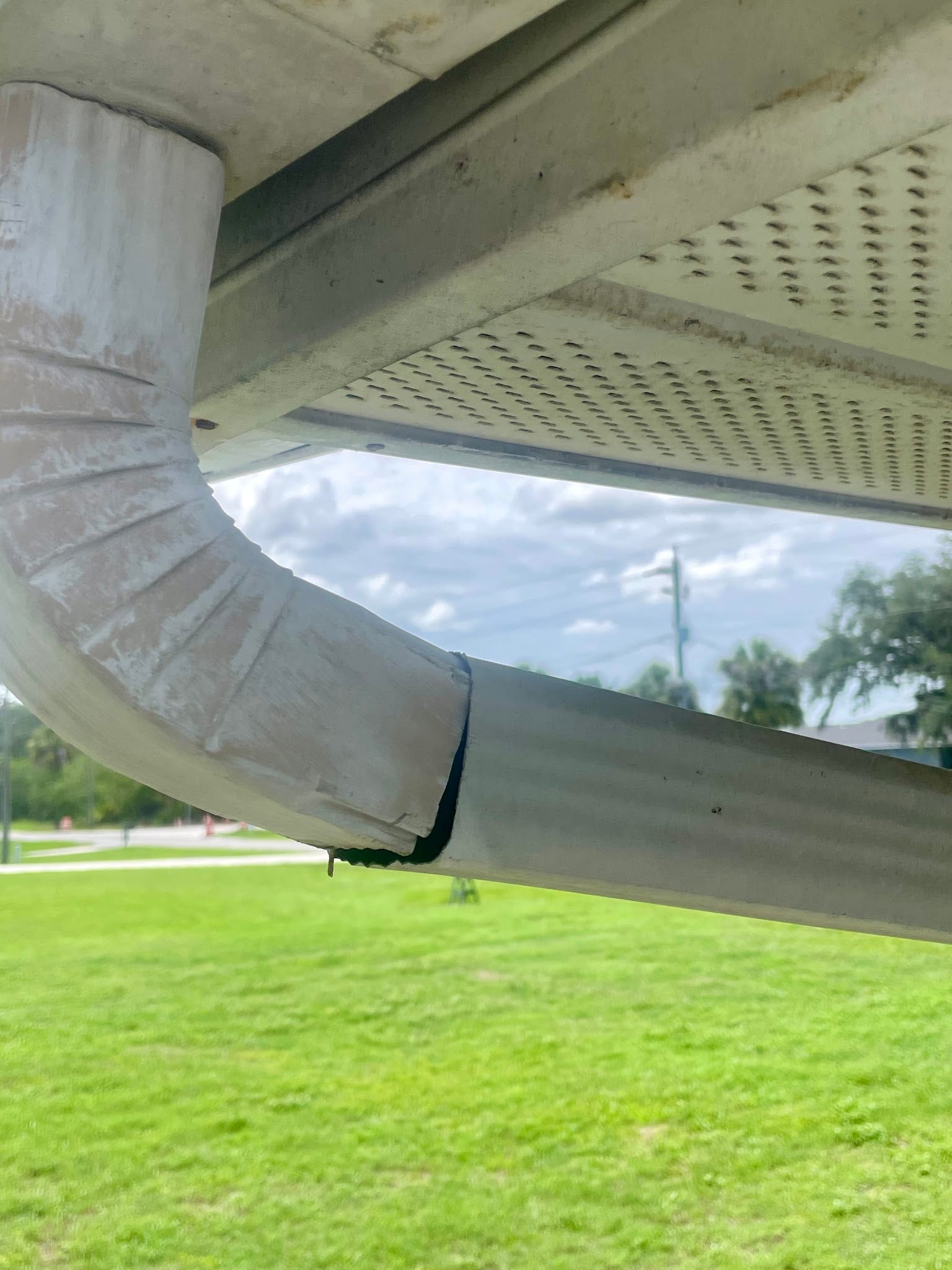 Damaged gutter downspout elbow with visible separation near roofline