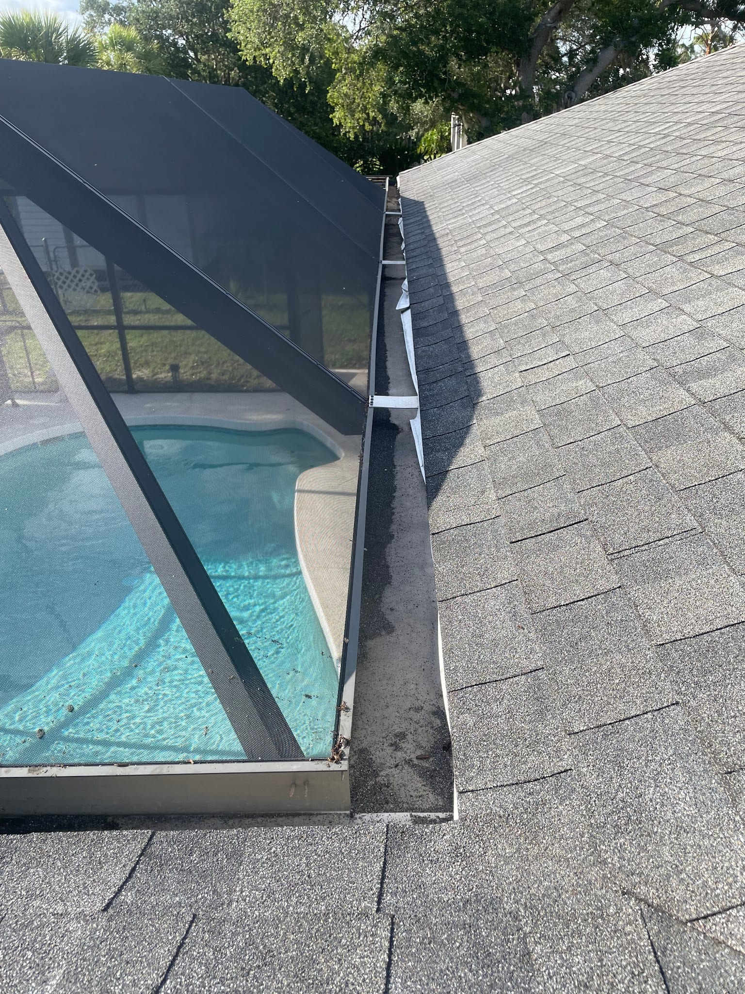 Dirty gutter along roofline beside screened pool enclosure needing cleaning