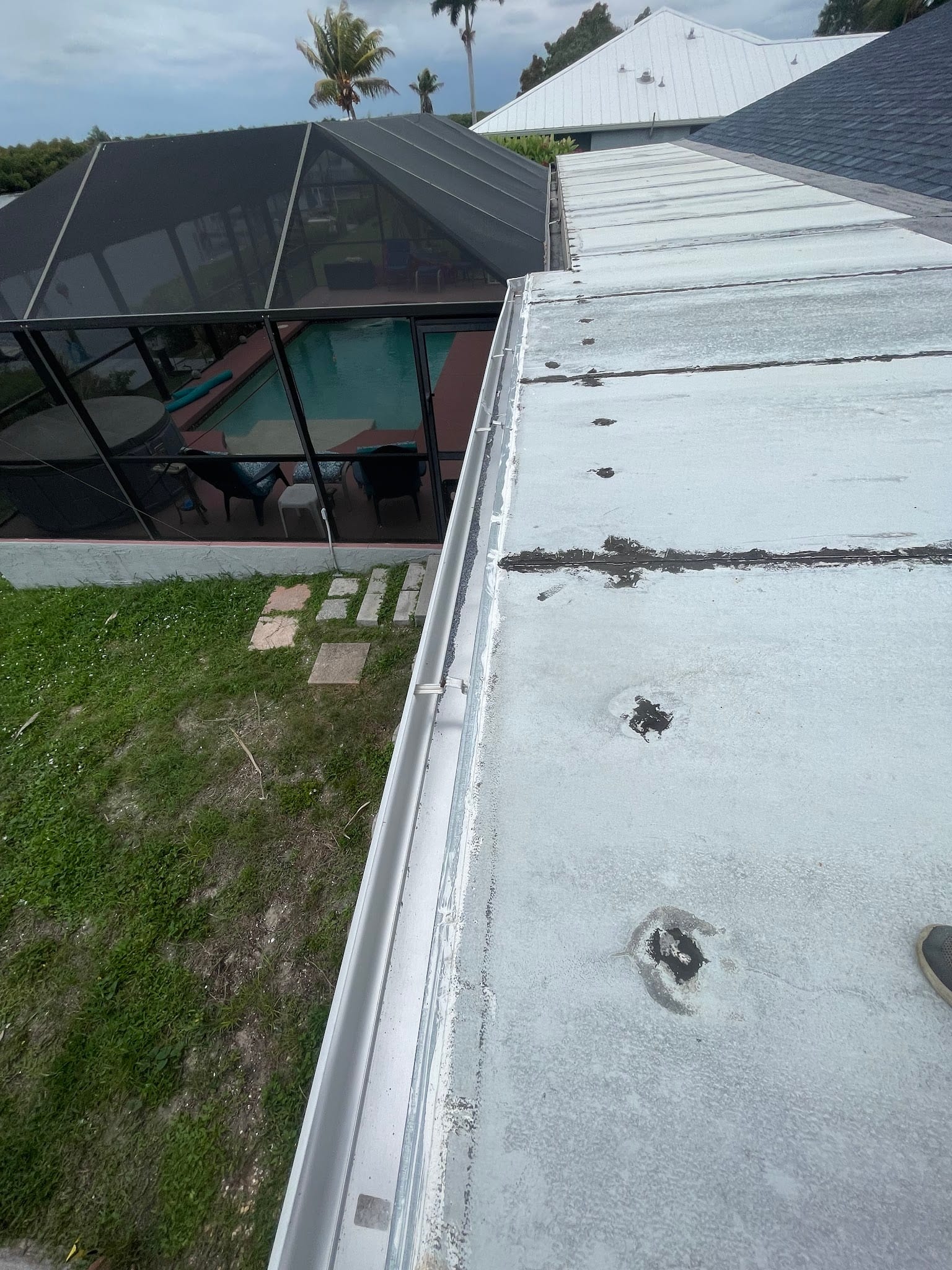 Aluminum rain gutter along flat roof edge with debris and damage visible