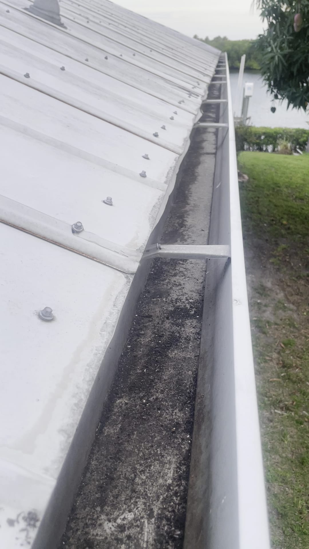 Debris-filled metal roof gutter needing cleaning in Port Charlotte