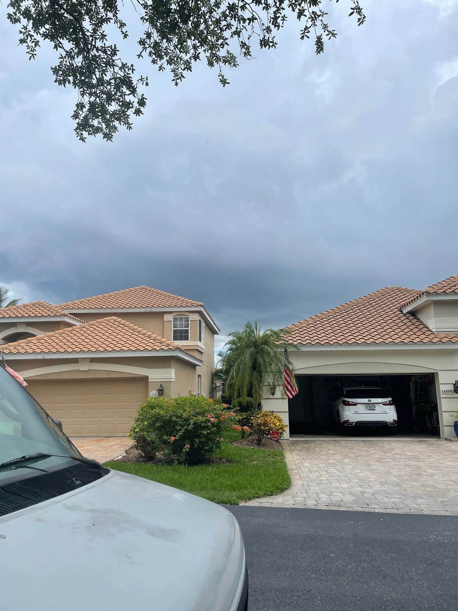 Two Florida homes with tile roofs and gutters under stormy skies.