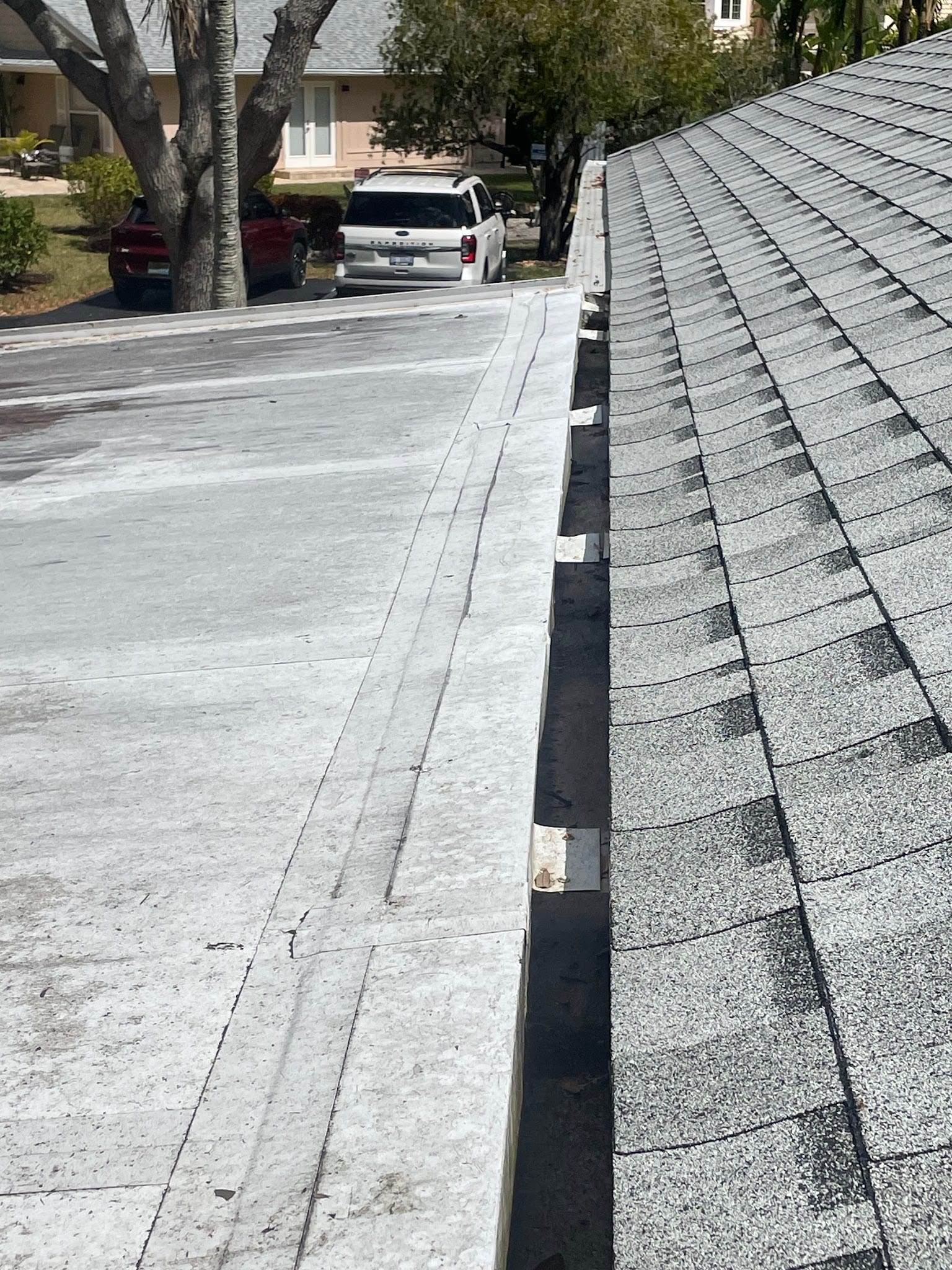 Clean gutters along flat and shingle roof junction in Port Charlotte