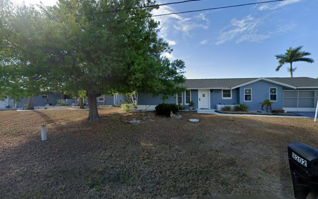 Single-story ranch home with large tree and dry front yard in Port Charlotte